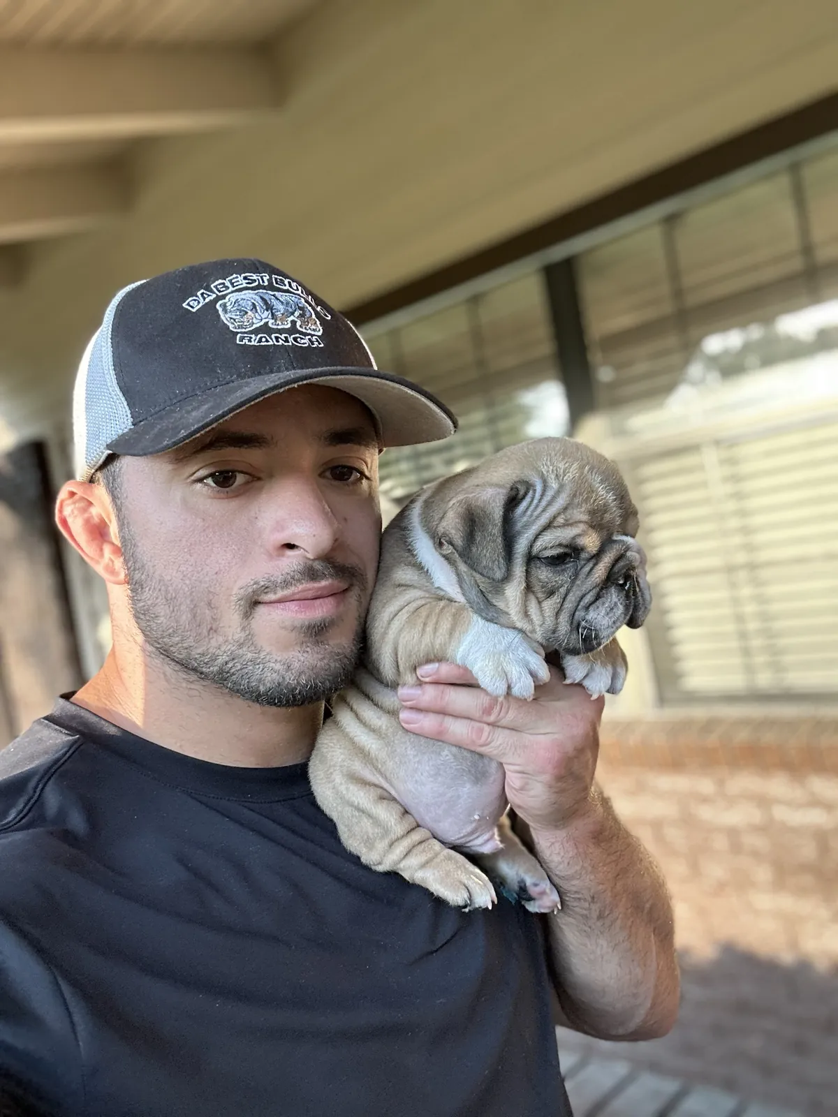 Jason Soares holding a fawn English bulldog puppy on his shoulder